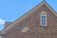 Brick gable detail with visible window with white trim and mullions