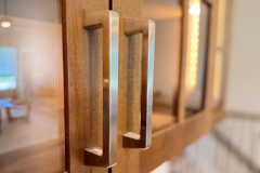 Close up of modern silver colored pulls on glsas door cabinets.