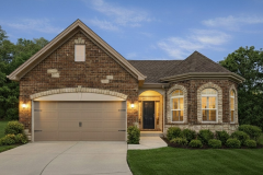 Brick villa exterior with gabled roof, arched windows, illuminated entry, and landscaped front yard.