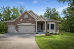 Brick ranch-style home with gabled roof, front porch columns, and a three‑car garage with separate single and double doors.